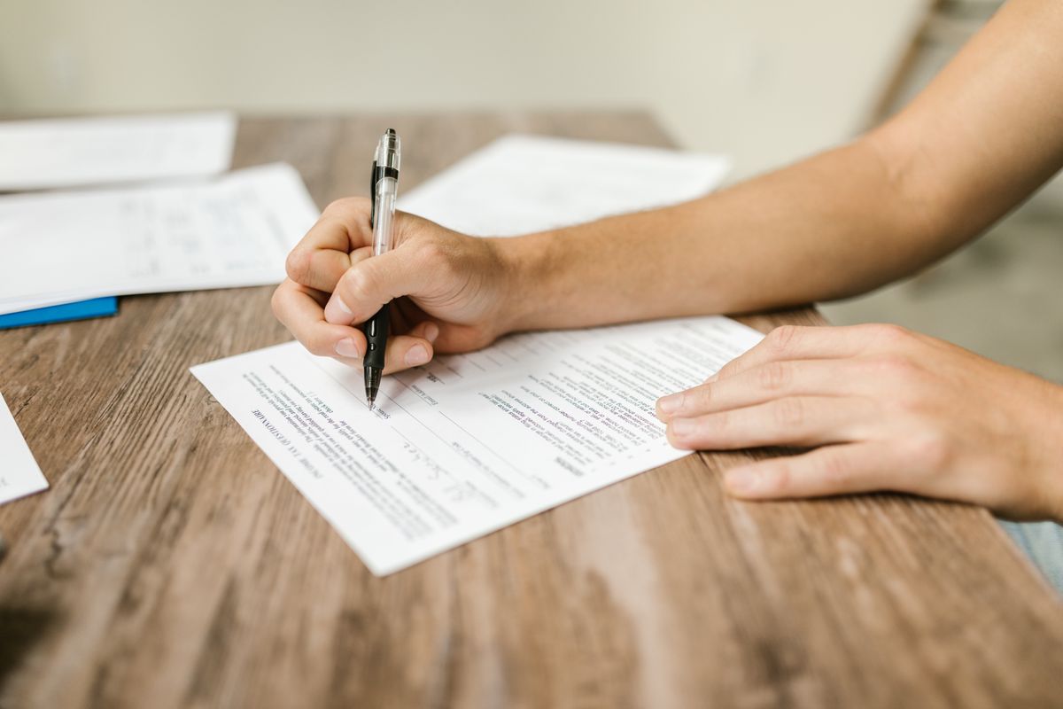 Main signant un document sur une table en bois