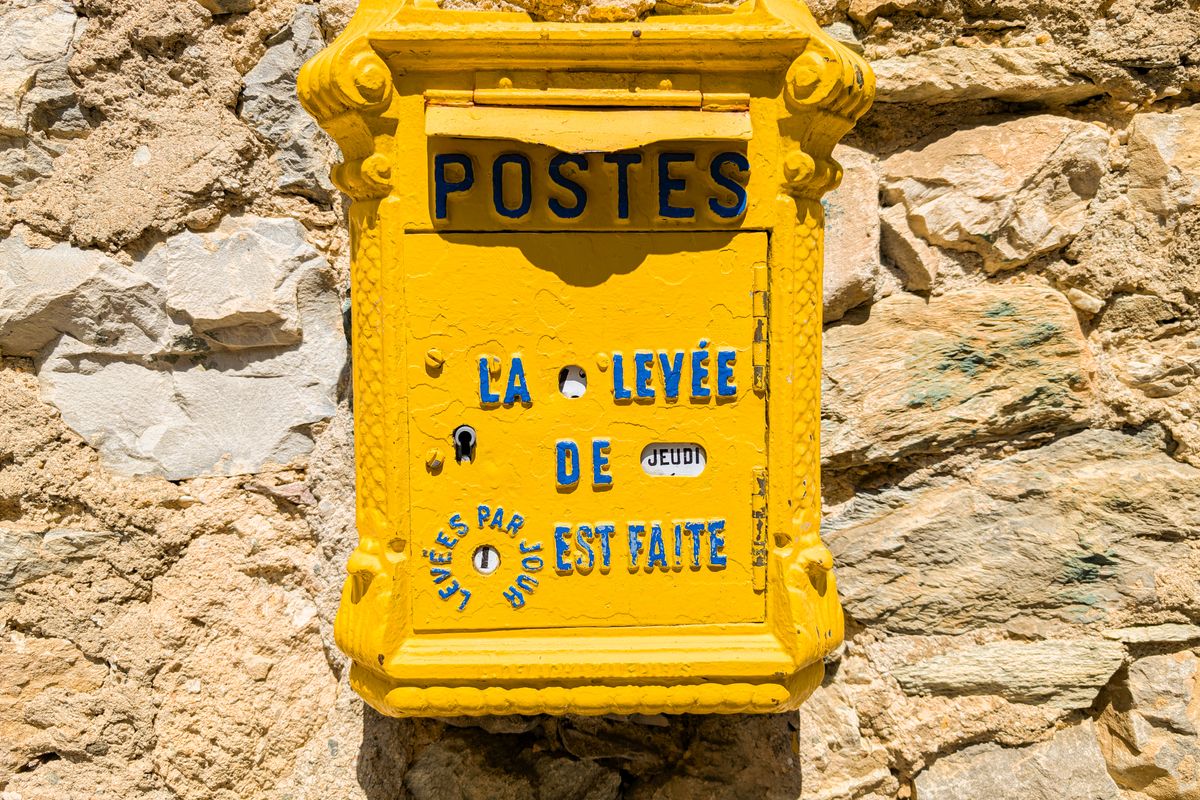 Boîte aux lettres jaune de La Poste sur un mur en pierre